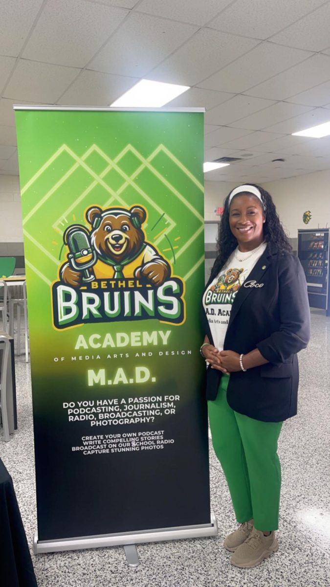 Ms. Lowery poses in front of the A.M.A.D (Academy of Media, Arts and Design) sign.